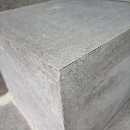 Szary stopień schodów wyłożony płytkami z widocznymi fugami.