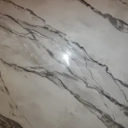 Ściana wykończona szpachlą dekoracyjną imitującą marmur z wyraźnymi, ciemnymi żyłami i błyszczącą powierzchnią.