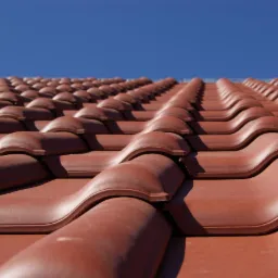 Ułożone dachówki ceramiczne w odcieniu miedzianym, widoczne z perspektywy żabiej, na tle błękitnego nieba.