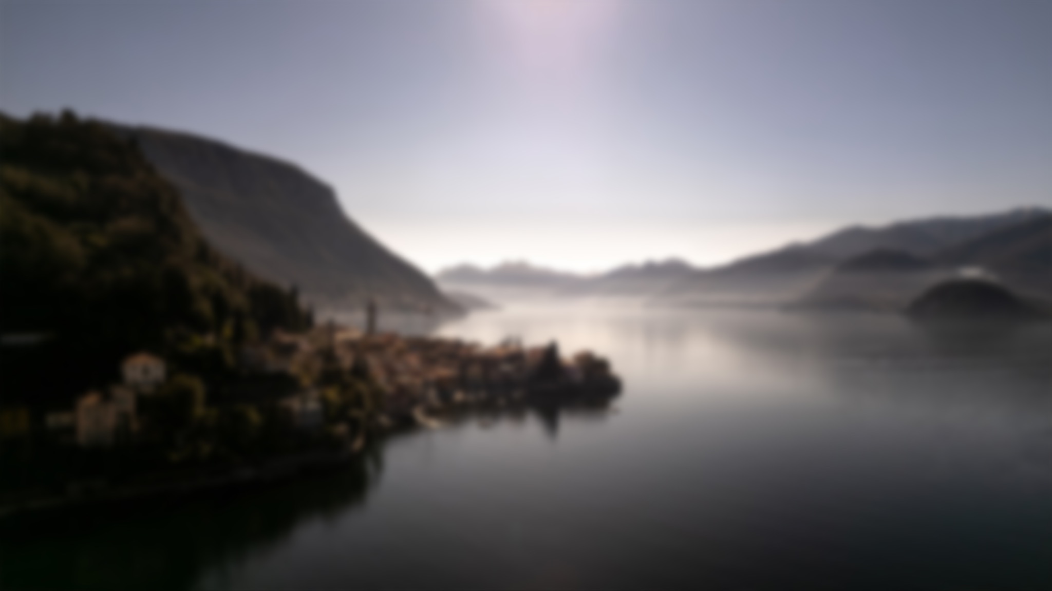 Panoramiczny widok na miasteczko położone nad jeziorem, otoczone górami we mgle, wczesnym rankiem.