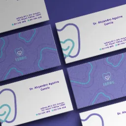 Zestaw wizytówek z logo i danymi kontaktowymi dentysty, utrzymanych w kolorystyce fioletowo-białej z turkusowymi akcentami, ułożonych pod kątem na fioletowym tle.
