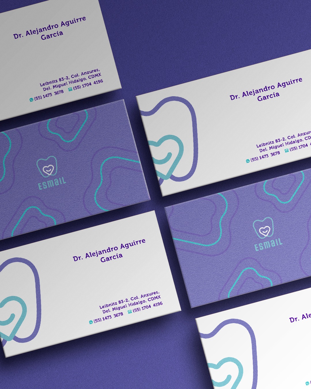 Zestaw wizytówek z logo i danymi kontaktowymi dentysty, utrzymanych w kolorystyce fioletowo-białej z turkusowymi akcentami, ułożonych pod kątem na fioletowym tle.