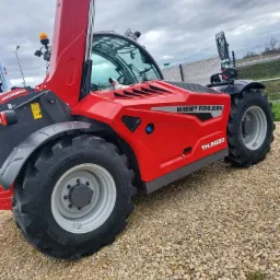 Czerwona ładowarka teleskopowa Massey Ferguson TH.6030 na żwirowym podłożu, widok z boku, pochmurne niebo w tle.