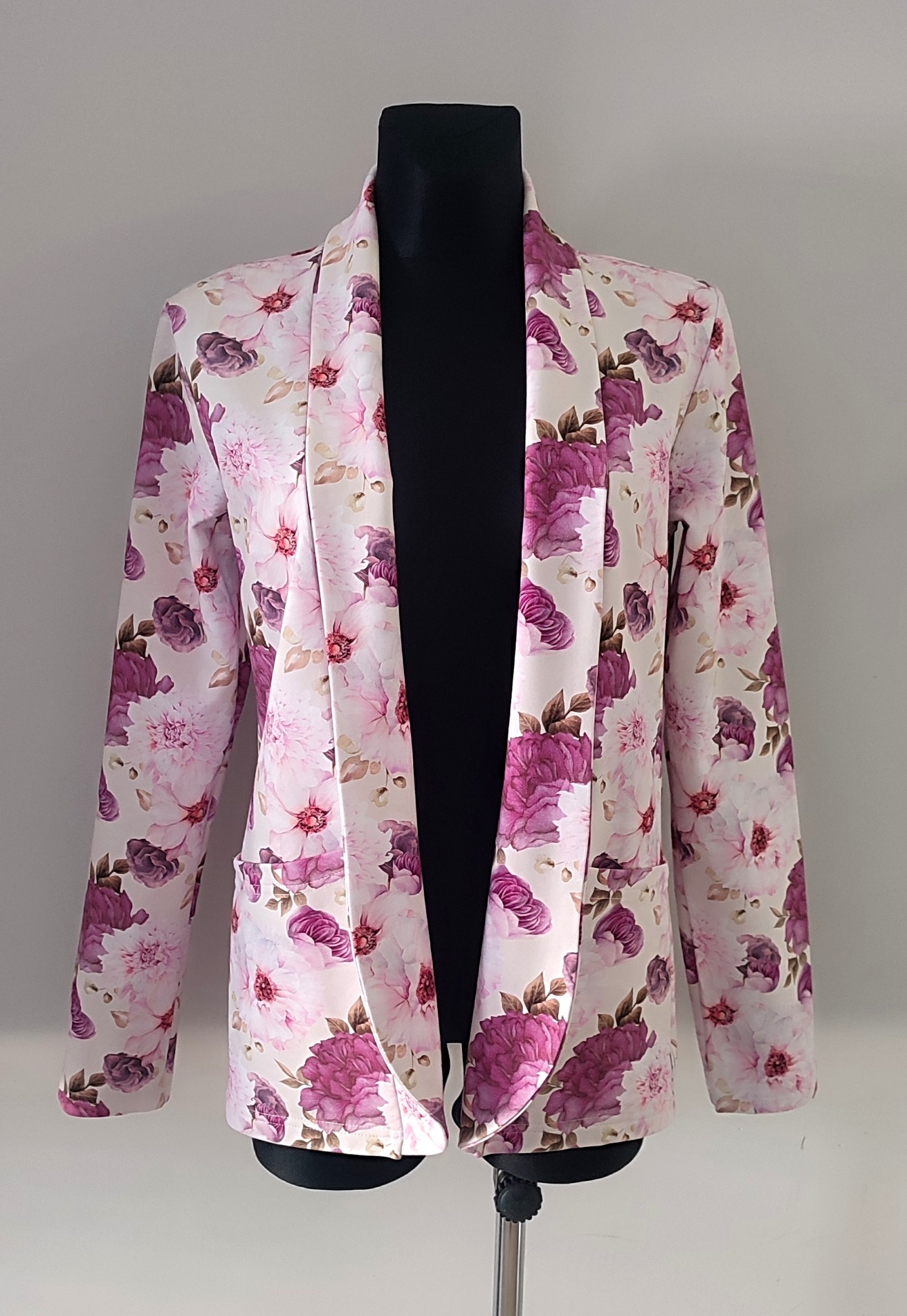 Żakiet damski w kwiaty, biało-różowy z fioletowymi akcentami, prezentowany na czarnym manekinie.