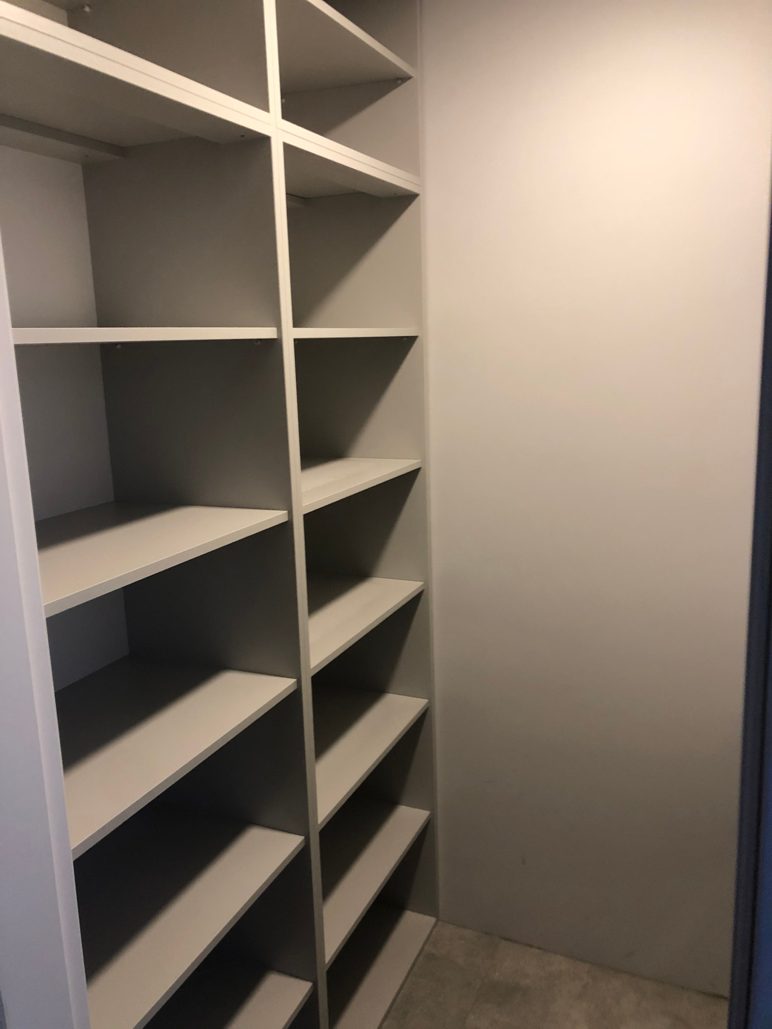 Pusta, jasnoszara szafa wnękowa z półkami, widok z dołu, wnętrze garderoby bez wyposażenia.