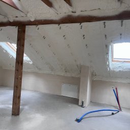 Delta Pur Izolacje - Poddasze po ociepleniu pianką PUR, widoczne okna dachowe i drewniany słup podtrzymujący konstrukcję dachu. Instalacja wodna na posadzce.