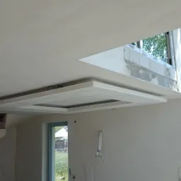 Wnętrze w trakcie remontu: sufit z elementami dekoracyjnymi i otwartymi przewodami elektrycznymi na ścianie.