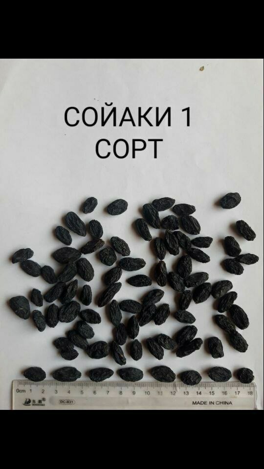Ciemne rodzynki ułożone na białym tle obok linijki, z napisem 'СОЙАКИ 1 СОРТ'.