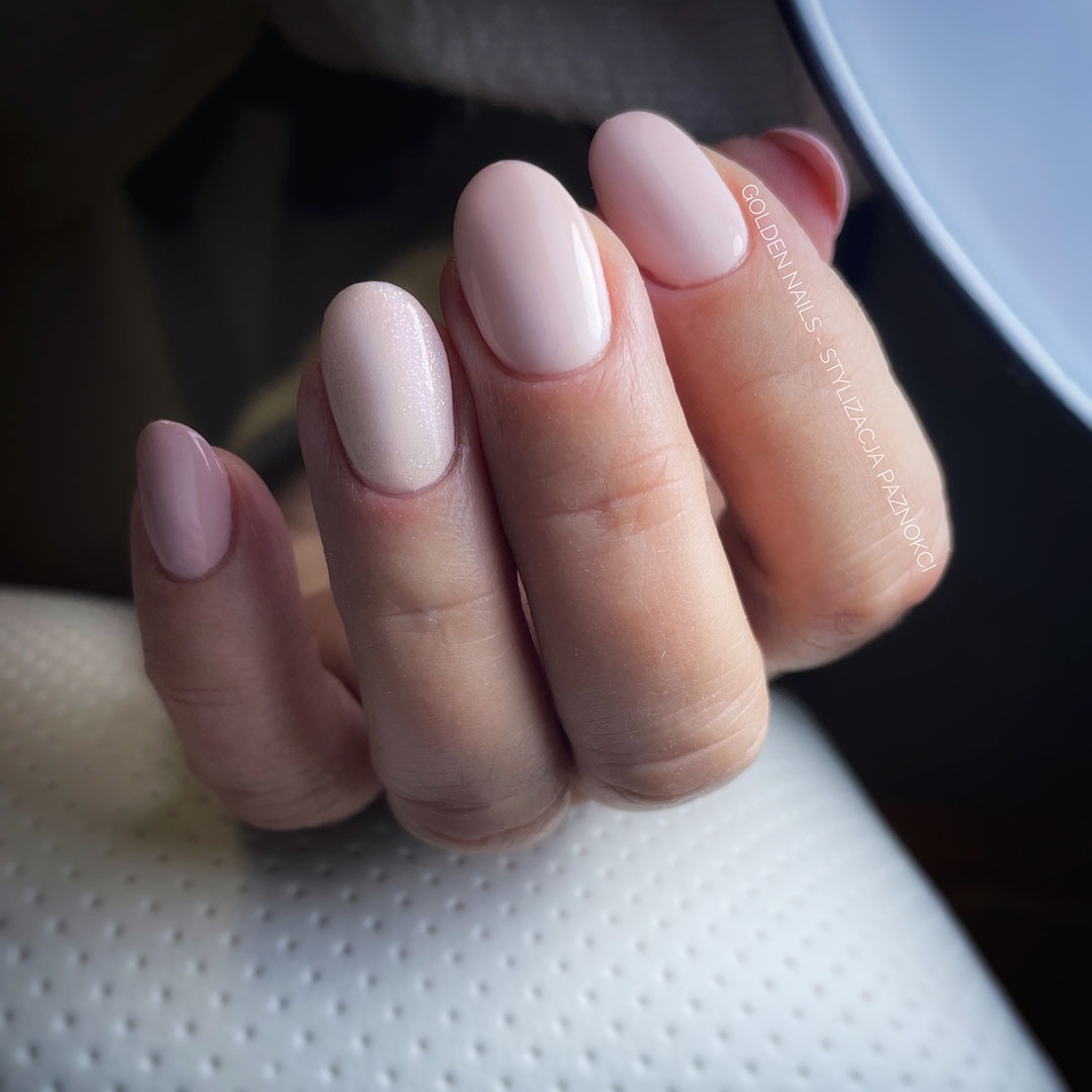 Dłoń z owalnymi paznokciami w odcieniach pudrowego różu, jeden paznokieć z delikatnym brokatem, wykonane w salonie stylizacji paznokci Golden Nails.