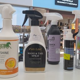 Sklep Jeździecki Gniady Koń - Różne butelki i pojemniki ze środkami do pielęgnacji koni, w tym szampony, odżywki i spraye do sierści, ustawione obok siebie na półce w sklepie zoologicznym, z cenami na żółtych naklejkach.