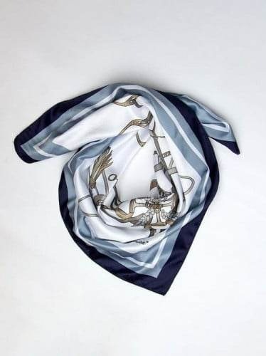 Jedwabna apaszka z motywem końskim, złożona na białym tle, z widocznymi odcieniami granatu i szarości w obramowaniu.