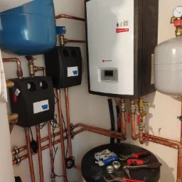 Węzeł cieplny z kotłem gazowym, zbiornikami, armaturą i rurami miedzianymi, narzędzia na zbiorniku, instalacja w kotłowni.
