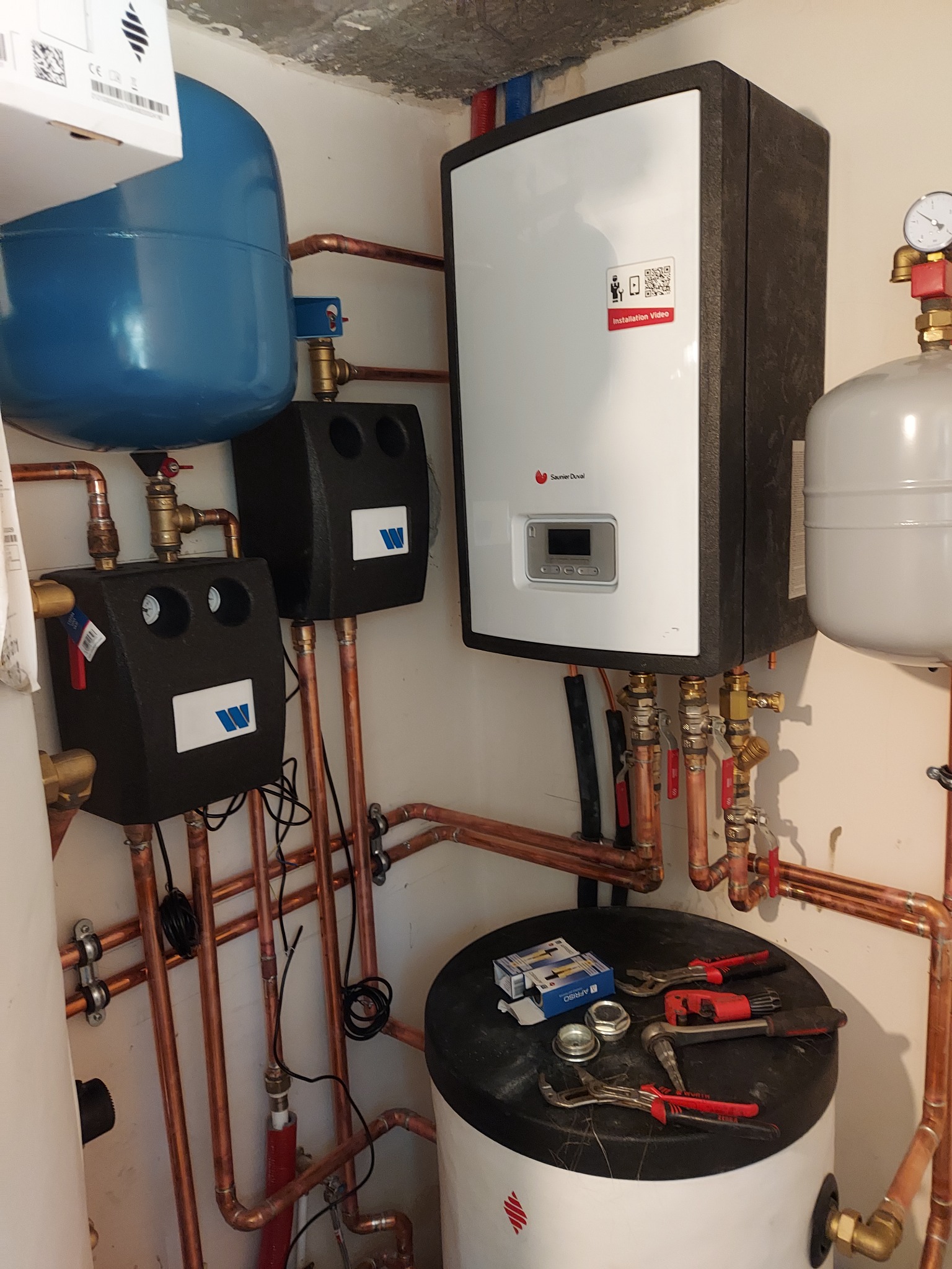 Węzeł cieplny z kotłem gazowym, zbiornikami, armaturą i rurami miedzianymi, narzędzia na zbiorniku, instalacja w kotłowni.