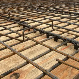 Siatka zbrojeniowa ułożona na drewnianym szalunku z użyciem plastikowych dystansów, przygotowana do zalania betonem.