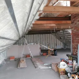 Ocieplanie poddasza pianką PUR w Prudniku, widoczne metalowe profile, częściowo zabudowane płyty gipsowo-kartonowe i porozrzucane narzędzia.