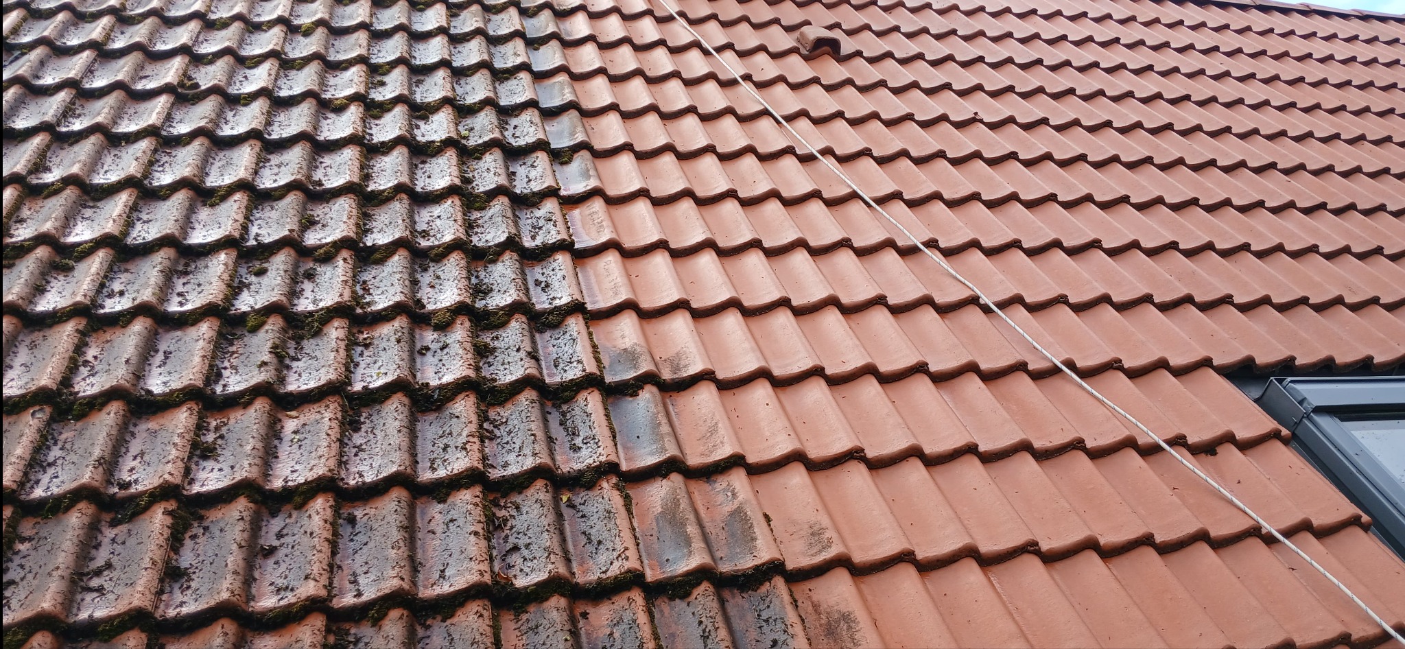 Częściowo wyczyszczony dach z czerwonej dachówki, widoczny mech i zabrudzenia. Połowa dachu umyta, prezentuje różnicę w wyglądzie.