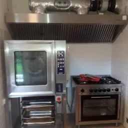 Profesjonalna kuchnia z piecem konwekcyjnym Hobart, kuchenką gazową i okapem z izolowanymi przewodami wentylacyjnymi.