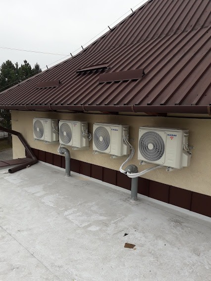 Cztery jednostki zewnętrzne klimatyzacji marki Kaisai zamontowane na dachu budynku w Sieprawiu, widoczne rury odprowadzające skropliny.