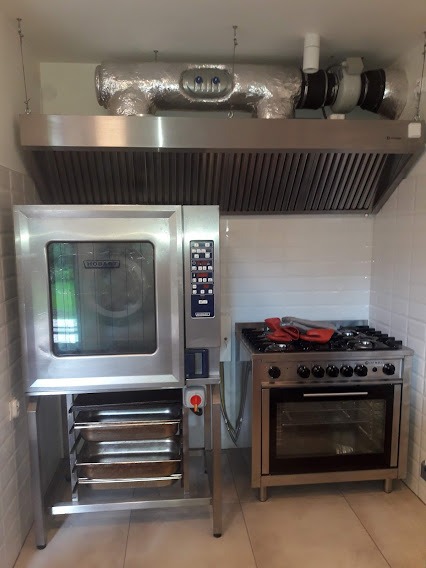 Profesjonalna kuchnia z piecem konwekcyjnym Hobart, kuchenką gazową i okapem z izolowanymi przewodami wentylacyjnymi.