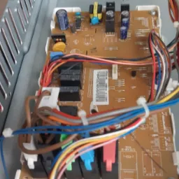 Wnętrze urządzenia z widoczną płytą sterującą, liczne przewody o różnych kolorach podłączone do złącz oznaczonych kolorami. Widoczny numer seryjny na płycie.