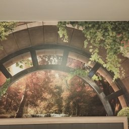 Firma Usługowa Złota Rączka Piotr Mikulewicz - Fototapeta na ścianie z motywem kamiennego łuku, zieleni i jesiennego lasu z wodospadem, tworząca iluzję okna z widokiem na naturę.