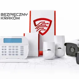 Zestaw urządzeń zabezpieczających: centrala alarmowa z klawiaturą, czujniki ruchu, kamery monitoringu oraz płytka drukowana, ułożone na planie architektonicznym. W tle logo firmy 'Bezpieczny Kraków'.
