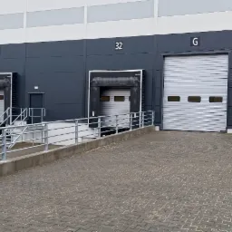 Zewnętrzny widok ramp załadunkowych magazynu z numerami 32, 33 i 34, oraz bramą garażową G.