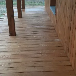 Drewniana elewacja budynku z widocznym tarasem z desek, z zewnątrz w pochmurny dzień.