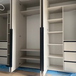 Arkadiusz Żołnowski - Jasna szafa na wymiar z szufladami i półkami, widok wnętrza, uchwyty w kolorze grafitowym. Podłoga zabezpieczona folią malarską, co sugeruje świeży montaż.