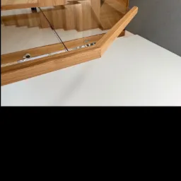 Otwarta szafka dębowa z blatem i szklaną półką, widoczna filiżanka. Dekoracyjne wykończenie frontów. Ujęcie z góry, z bliska.