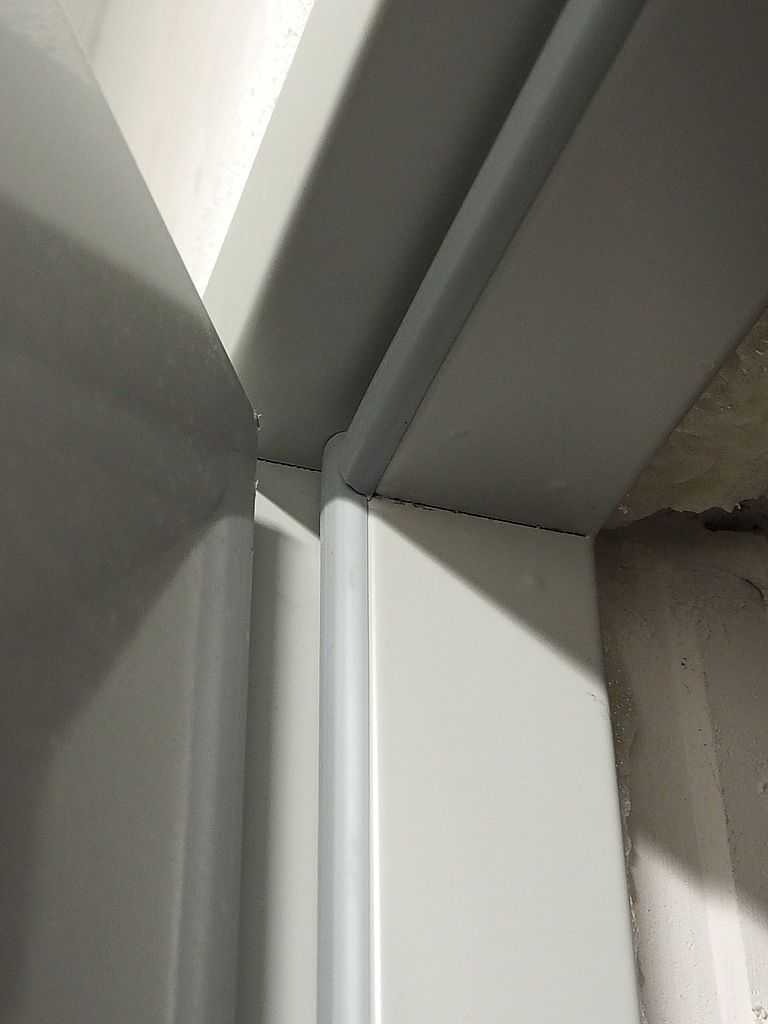 Detal montażu ościeżnicy drzwi technicznych w surowym otworze ściennym, widoczne elementy mocujące i niedokończone wykończenie.