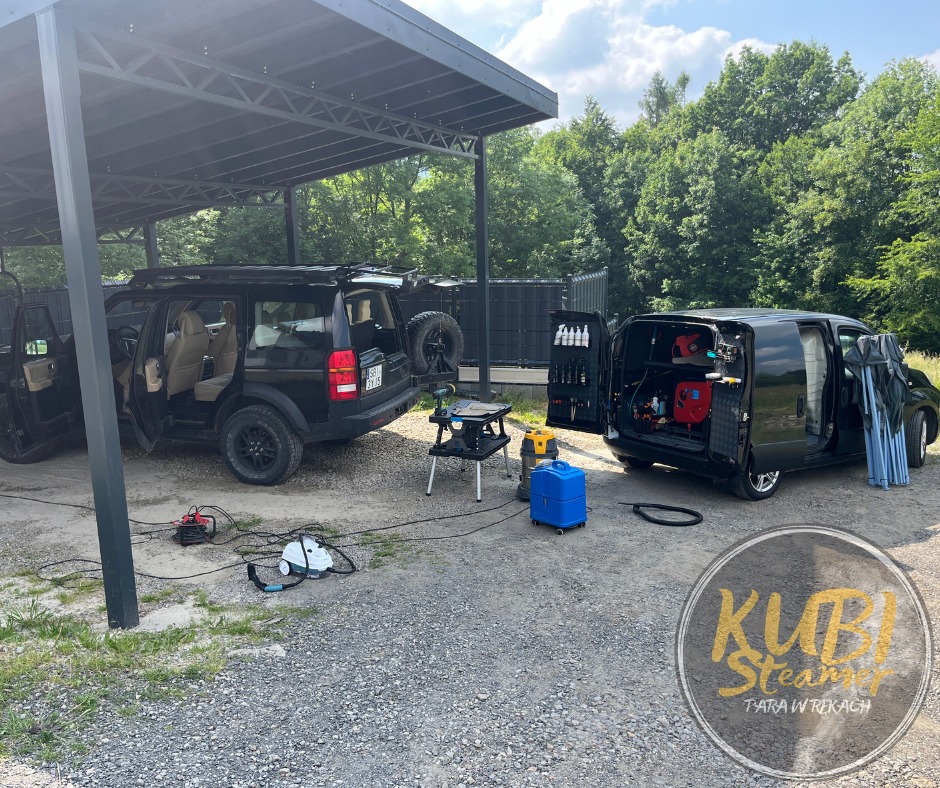 Czarny Land Rover i czarny van z otwartymi drzwiami, sprzęt do czyszczenia parowego na zewnątrz, logo firmy w prawym dolnym rogu.