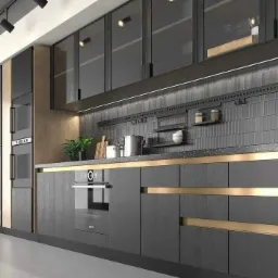 Nowoczesna kuchnia w odcieniach szarości z elementami złota, wyposażona w zabudowane sprzęty AGD i przeszklone szafki wiszące z oświetleniem punktowym.