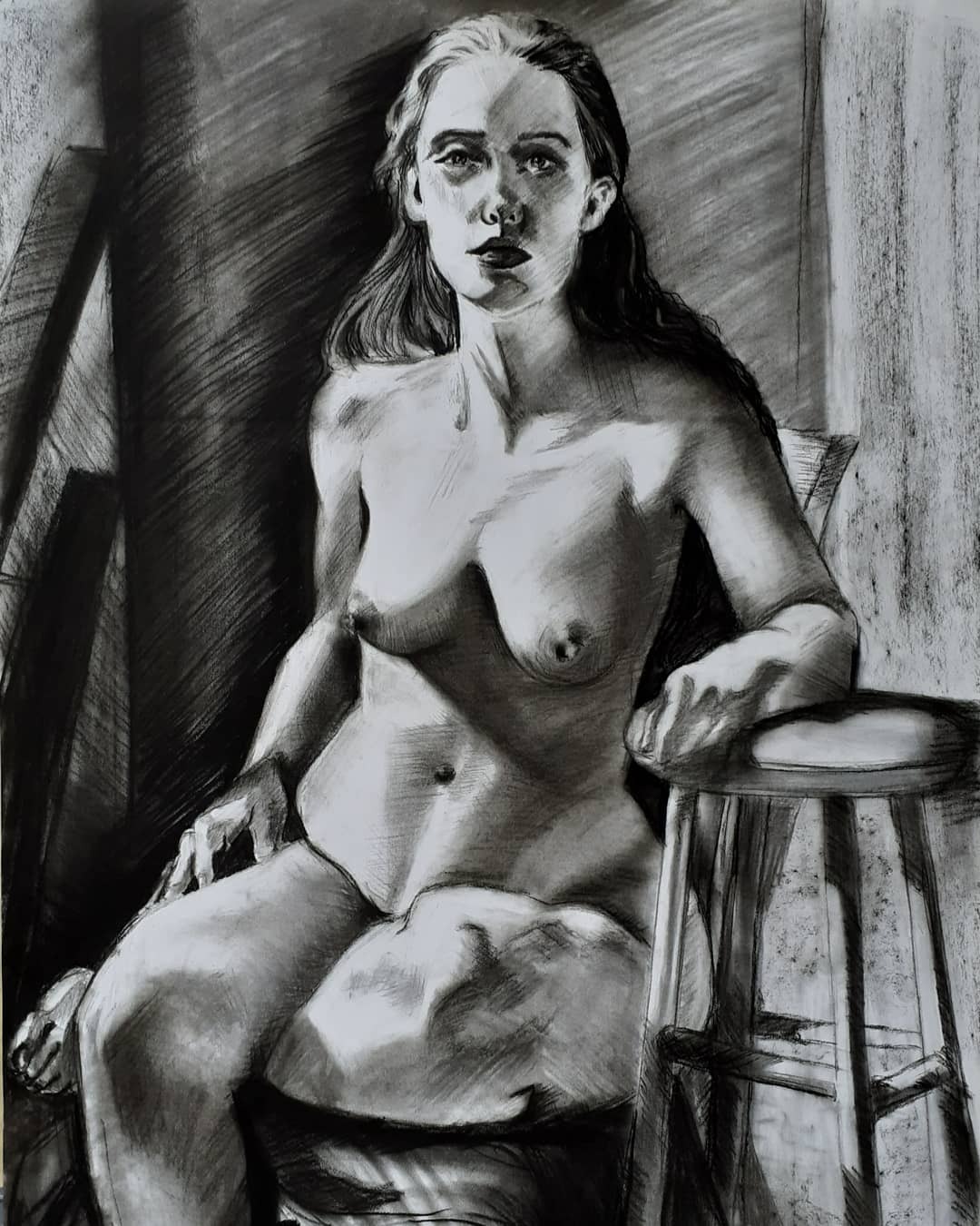 Szkic węglem przedstawiający siedzącą, nagą kobietę na stołku, z mocnym światłocieniem podkreślającym kontury i detale ciała.