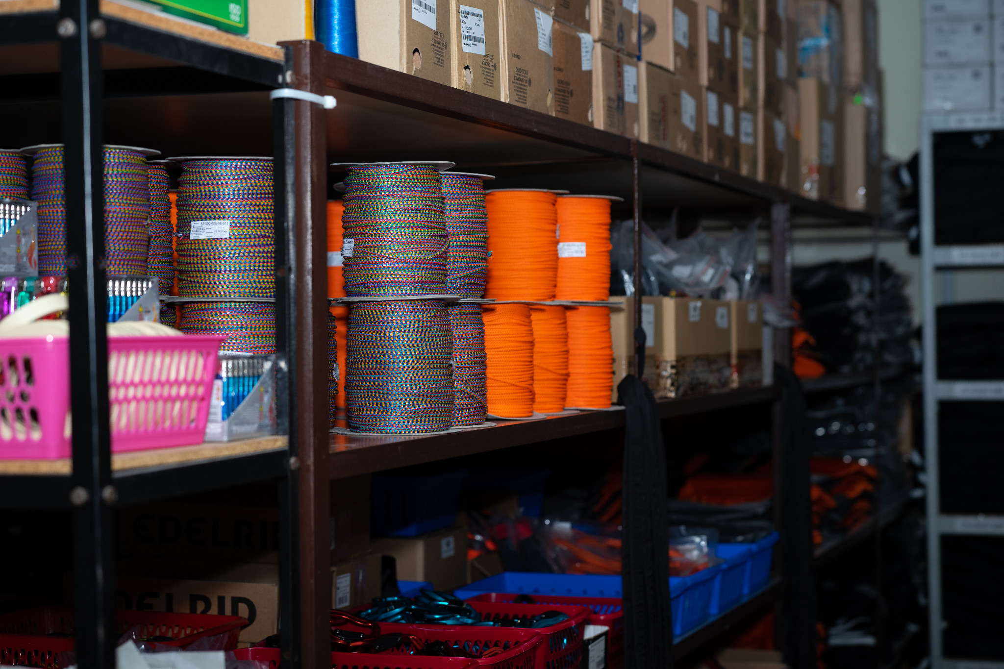 Skladowane na półkach szpule kolorowych i pomarańczowych nici w magazynie firmy z Szubina, gotowe do użycia w produkcji odzieży.