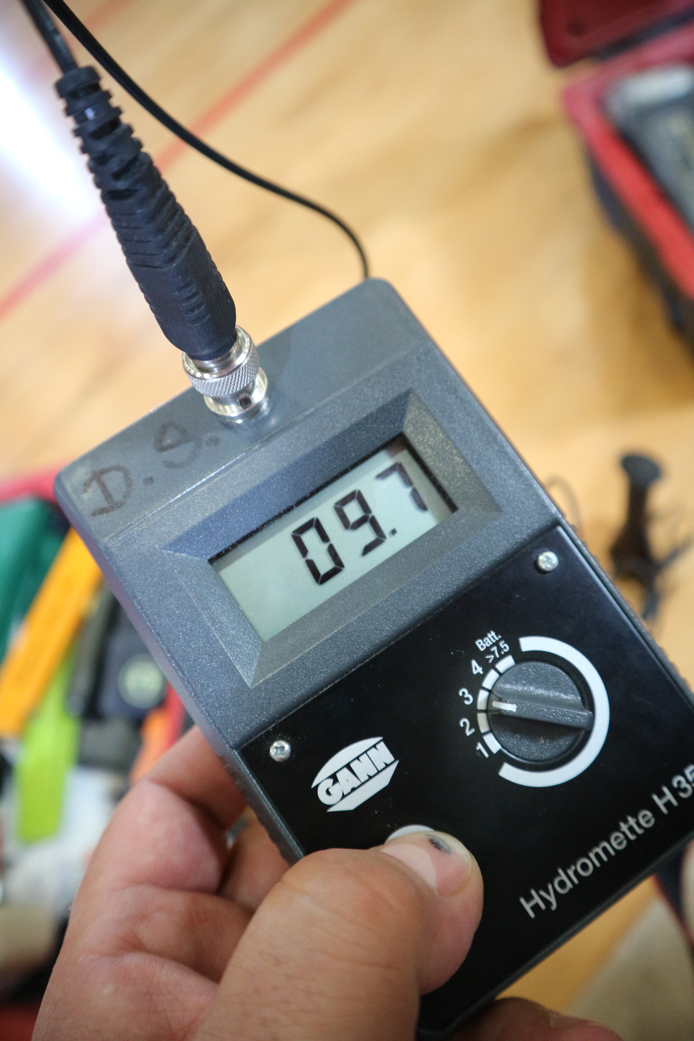 Miernik wilgotności GANN Hydromette H35 w dłoni, wskazujący wartość 09.7, z widocznym kablem podłączonym do urządzenia i śladami użytkowania na obudowie.