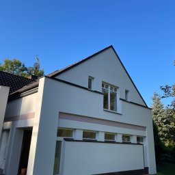 BANDINVESTMENT - Nowoczesny dom z białą elewacją, akcentami w postaci różowego paska, widoczne puszki z farbą i drabina, sugerujące świeżo zakończone prace malarskie.