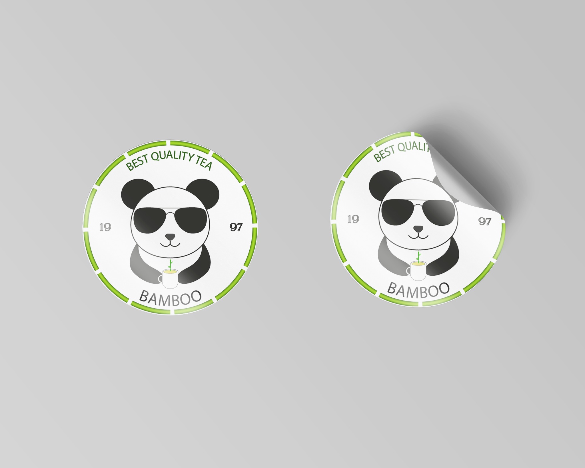 Dwa okrągłe, białe naklejki z logo pandy w okularach, trzymającej filiżankę z bambusem, otoczone zielonym obramowaniem z napisem 'Best Quality Tea' i 'Bamboo', jedna z naklejek jest częściowo...
