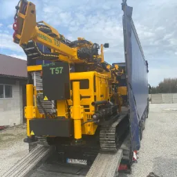 Żółta wiertnica Beretta T57 na gąsienicach, załadowana na lawetę samochodu ciężarowego z plandeką, widok z tyłu, na tablicy rejestracyjnej widoczny numer PKR YH46.