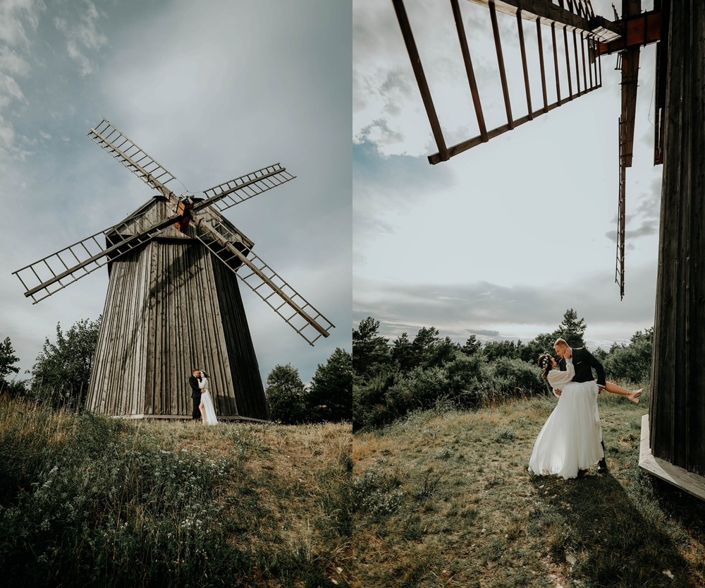 Para młoda pozuje przy drewnianym wiatraku w plenerze, ona w białej sukni, on w czarnym garniturze, ujęcie z dwóch perspektyw.