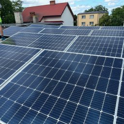 VIA-SYSTEM - Instalacja paneli fotowoltaicznych na dachu domu jednorodzinnego z widocznym fragmentem pracownika w odblaskowej kamizelce i neonowych spodenkach.