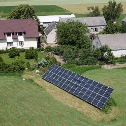 VIA-SYSTEM - Panel słoneczny zainstalowany na trawniku przed wiejskim domem z budynkami gospodarczymi w tle, widok z góry.