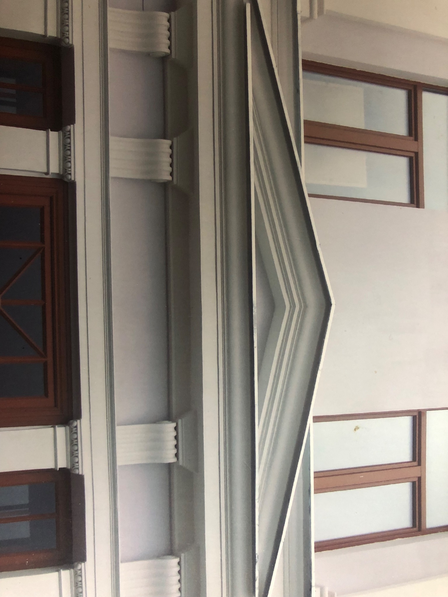 Fragment elewacji z drewnianymi oknami i dekoracyjnymi elementami architektonicznymi, widoczne detale sztukaterii.