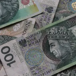 Stos banknotów 100 zł z wizerunkiem króla Władysława Jagiełły, ułożonych warstwami, z widocznymi detalami zabezpieczeń i nominałów.