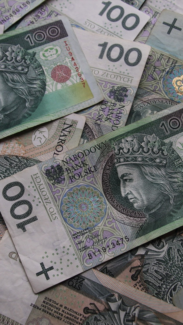 Stos banknotów 100 zł z wizerunkiem króla Władysława Jagiełły, ułożonych warstwami, z widocznymi detalami zabezpieczeń i nominałów.