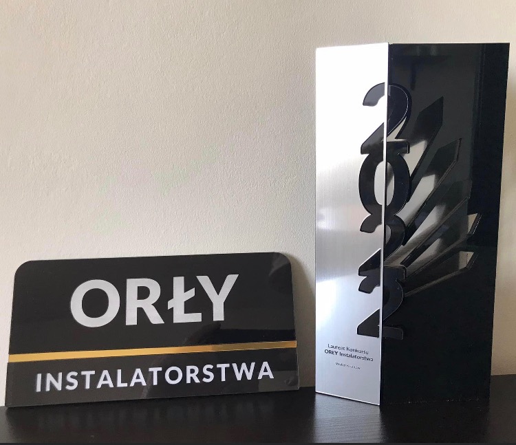 Nagroda 'Orły Instalatorstwa' z 2022 roku, srebrno-czarna statuetka i tabliczka z nazwą konkursu, na ciemnym tle.