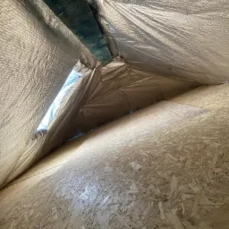 Wnętrze poddasza z widoczną izolacją termiczną (folia aluminiowa) i płytami OSB na ścianach szczytowych.