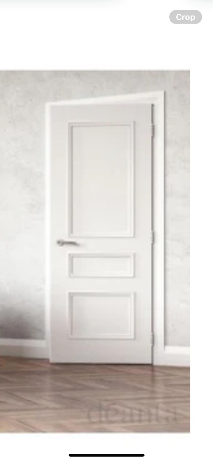 Białe drzwi wewnętrzne z dekoracyjnymi ramkami, srebrna klamka, parkiet w jodełkę, ściana w odcieniach szarości.