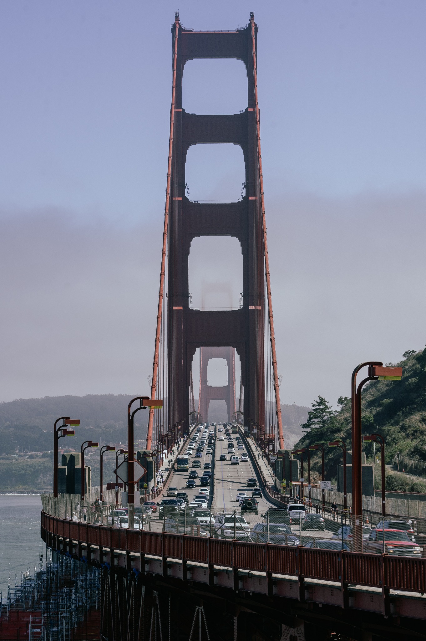Widok z dołu na przęsła mostu Golden Gate z gęstym ruchem samochodowym, z elementami rusztowania widocznymi po lewej stronie.