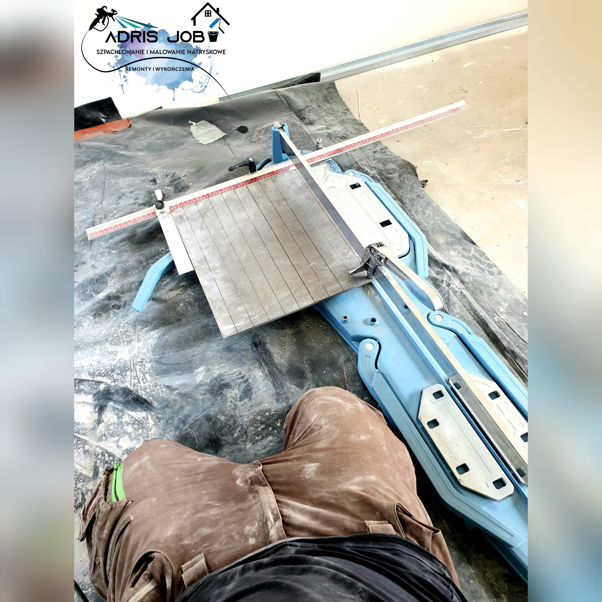 Przycięta płytka ceramiczna na profesjonalnej maszynce do cięcia, widoczne ślady po cięciu, w tle robocze ubranie glazurnika, folia ochronna na podłodze i logo firmy na ścianie.